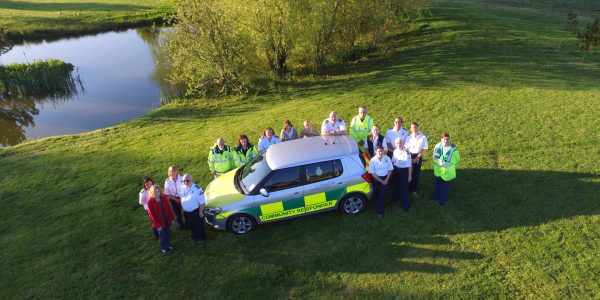 The Vale Responders team stood around a community responder car, taken from above with a drone
