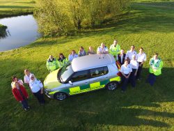 The Vale Responders team stood around a community responder car, taken from above with a drone